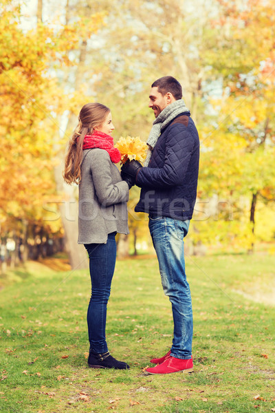 smiling couple with bunch of leaves in autumn park Stock photo © dolgachov