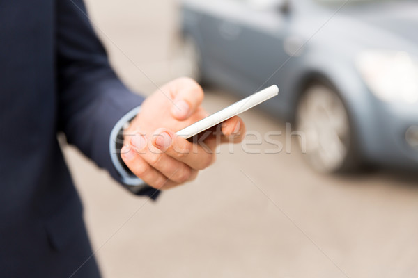 Stock photo: close up of man hand with smartphone and car