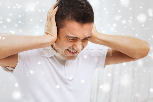 unhappy man closing his ears by hands at home Stock photo © dolgachov