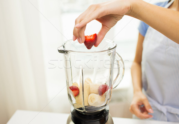 Stock photo: close up of woman with blender making fruit shake