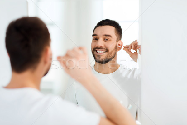 man cleaning ear with cotton swab at bathroom Stock photo © dolgachov