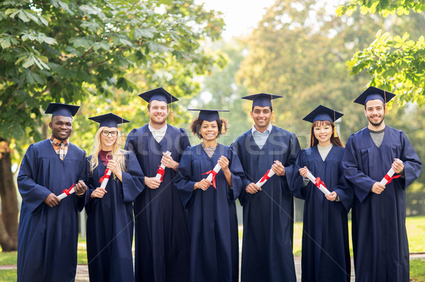 happy students in mortar boards with diplomas Stock photo © dolgachov