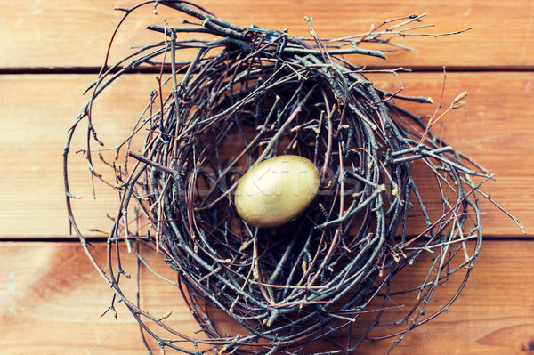 close up of golden easter egg in nest on wood Stock photo © dolgachov