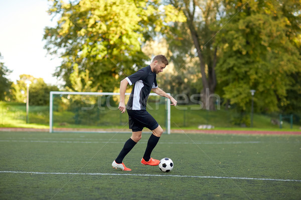 soccer player playing with ball on football field Stock photo © dolgachov