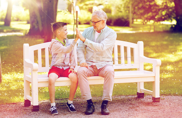 old man and boy making high five at summer park Stock photo © dolgachov