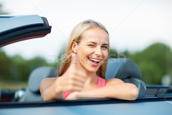 Stock photo: happy young woman in convertible car thumbs up