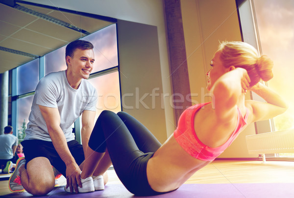 Stock photo: woman with personal trainer doing sit ups in gym