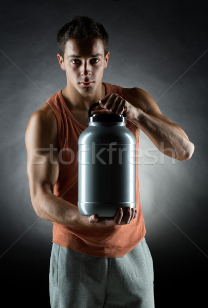 young male bodybuilder holding jar with protein Stock photo © dolgachov