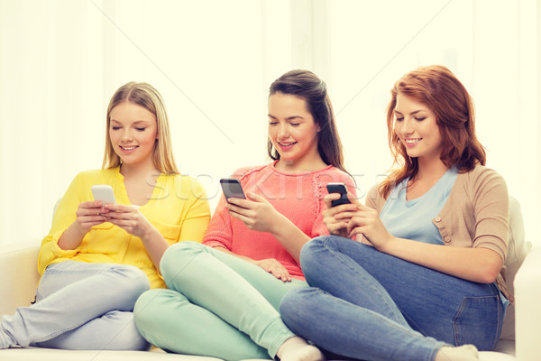 Stock photo: smiling teenage girls with smartphones at home