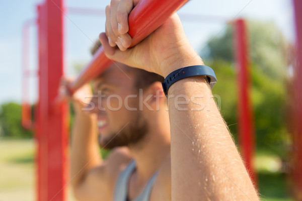 young man exercising on horizontal bar outdoors Stock photo © dolgachov