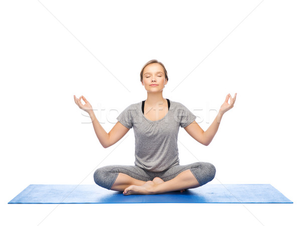 woman making yoga meditation in lotus pose on mat Stock photo © dolgachov