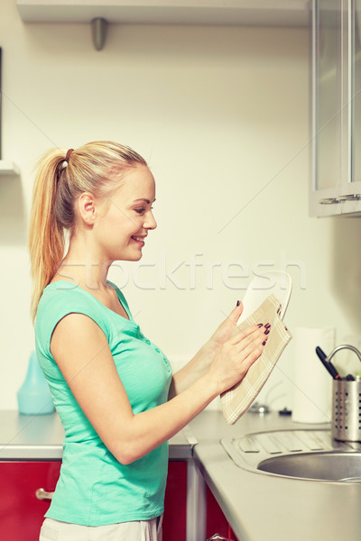 happy woman wiping dishes at home kitchen Stock photo © dolgachov