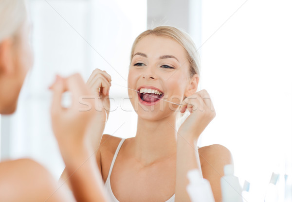 woman with dental floss cleaning teeth at bathroom Stock photo © dolgachov