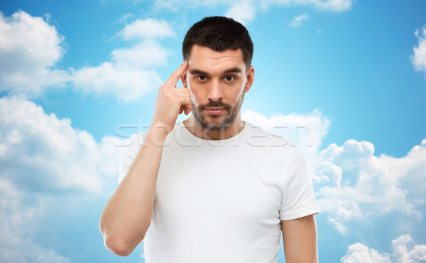 man with finger at temple over blue sky background Stock photo © dolgachov