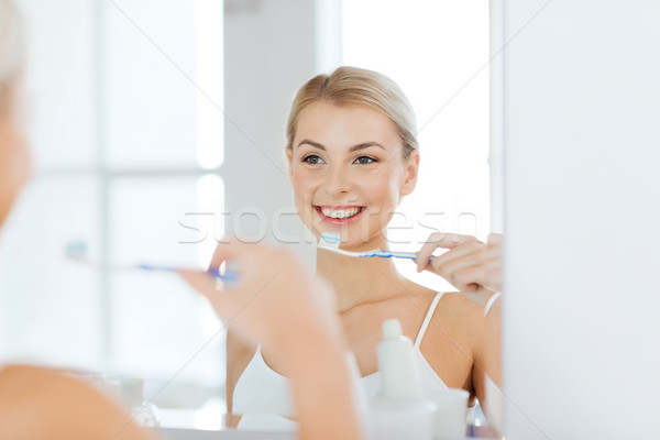 Femme brosse à dents nettoyage dents salle de bain [[stock_photo]] © dolgachov