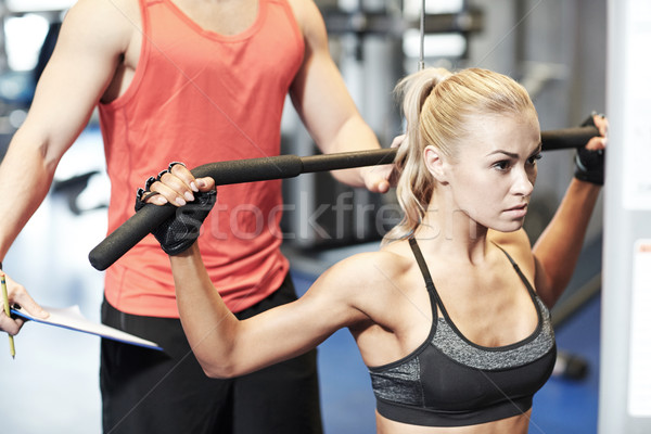 Stock photo: man and woman flexing muscles on gym machine