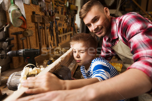 father and little son with wood plank at workshop Stock photo © dolgachov