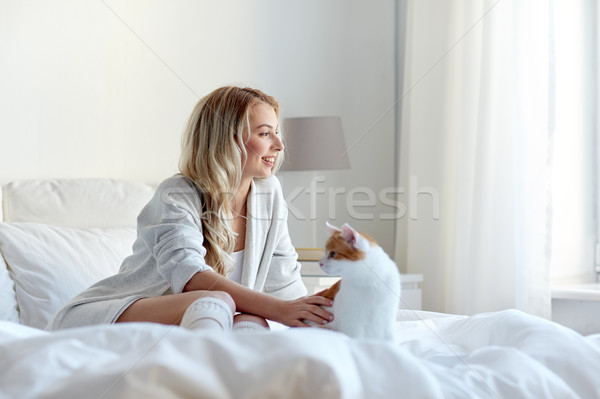 happy young woman with cat in bed at home Stock photo © dolgachov