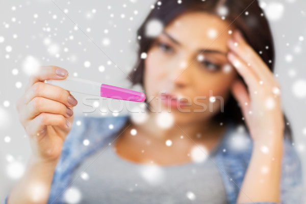 Stock photo: close up of sad woman with home pregnancy test