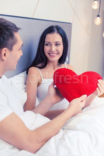 smiling couple in bed with red heart shape pillow Stock photo © dolgachov