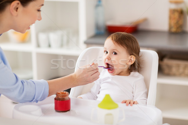 happy mother feeding baby with puree at home Stock photo © dolgachov