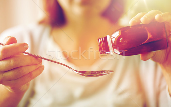 woman pouring medication from bottle to spoon Stock photo © dolgachov