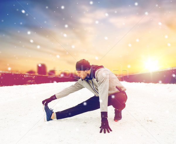 man exercising and stretching leg on winter bridge Stock photo © dolgachov
