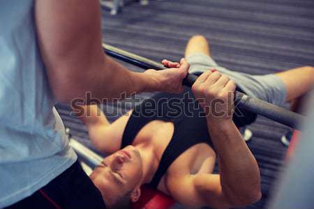 two young men with barbell flexing muscles in gym Stock photo © dolgachov