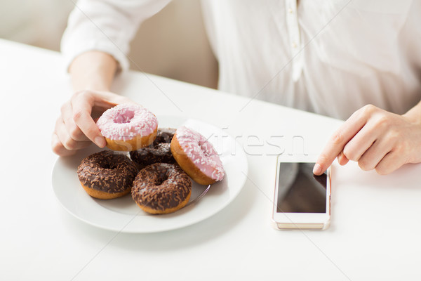 close up of hands with smart phone and donuts Stock photo © dolgachov