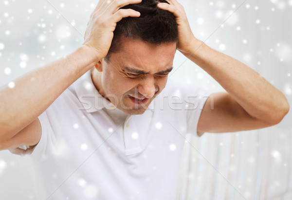 unhappy man suffering from head ache at home Stock photo © dolgachov