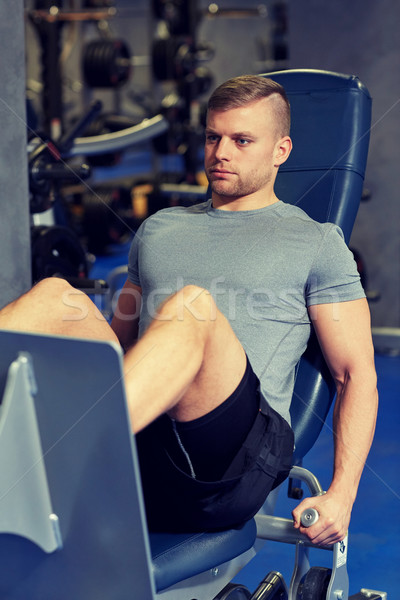 man flexing leg muscles on gym machine Stock photo © dolgachov