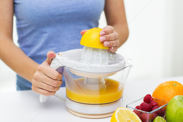 close up of woman squeezing fruit juice at home Stock photo © dolgachov