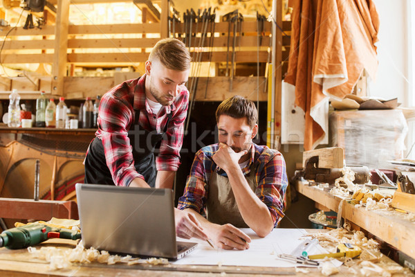 carpenters with laptop and blueprint at workshop Stock photo © dolgachov