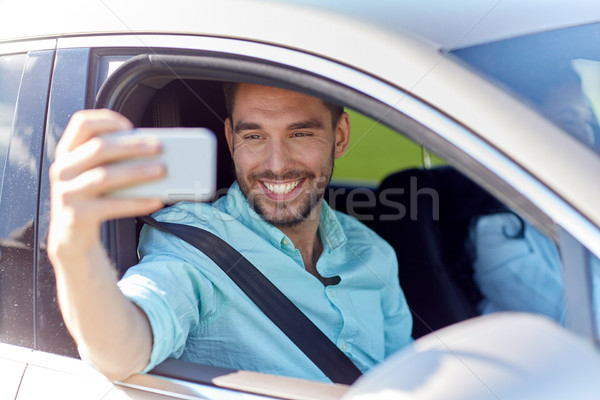 Heureux souriant homme smartphone conduite voiture [[stock_photo]] © dolgachov