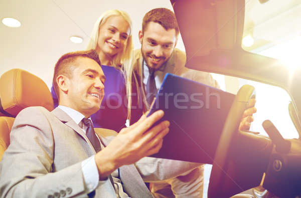 happy couple with car dealer in auto show or salon Stock photo © dolgachov