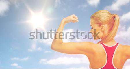 happy sporty woman showing biceps over sky and sun Stock photo © dolgachov