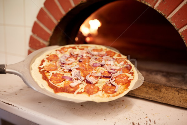 peel placing pizza into oven at pizzeria Stock photo © dolgachov
