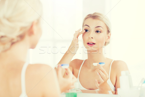 young woman putting on contact lenses at bathroom Stock photo © dolgachov