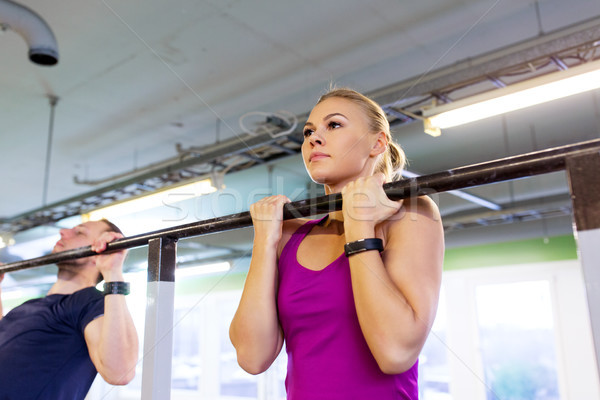 couple doing pull-ups at horizontal bar in gym Stock photo © dolgachov