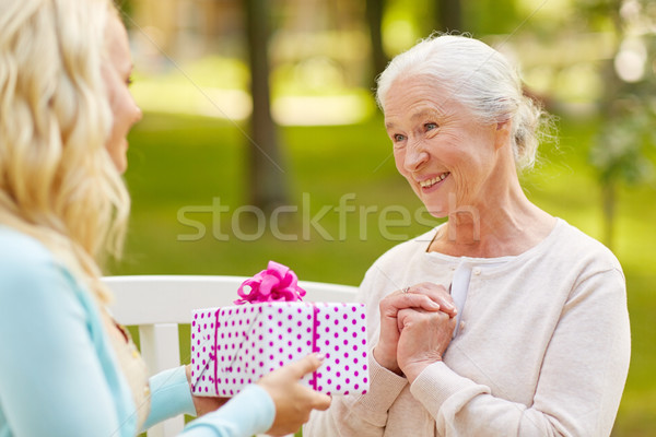daughter giving present to senior mother at park Stock photo © dolgachov
