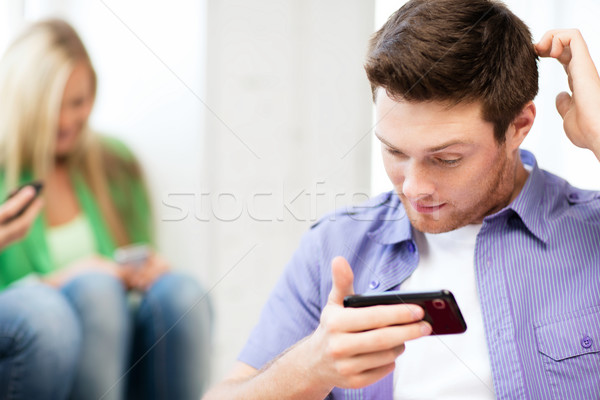 Student patrząc telefonu piśmie coś technologii Zdjęcia stock © dolgachov