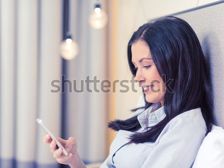 Stock photo: happy businesswoman with smartphone in hotel room