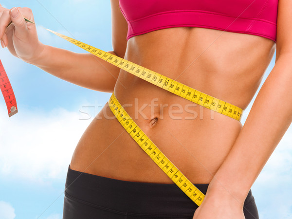 close up of trained belly with measuring tape Stock photo © dolgachov