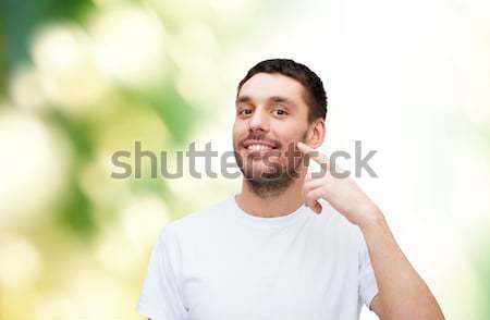 Stock photo: smiling young handsome man pointing to cheek