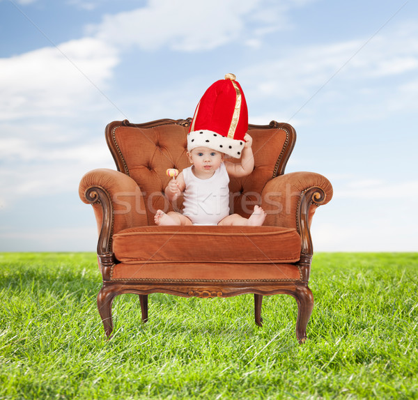 baby in royal hat with lollipop sitting on chair Stock photo © dolgachov