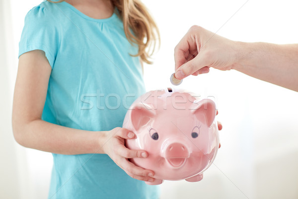 close up of girl with piggy bank putting coin Stock photo © dolgachov