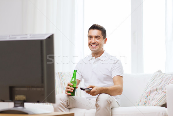 Sorridente homem assistindo tv potável cerveja Foto stock © dolgachov