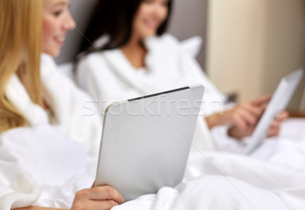 happy women in bathrobes with tablet pc at hotel Stock photo © dolgachov