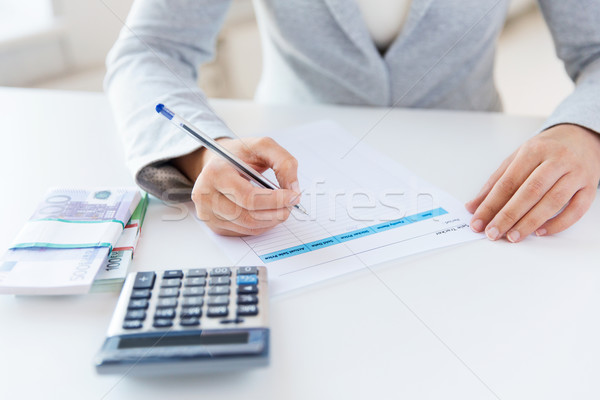 Stock photo: close up of hands counting money with calculator