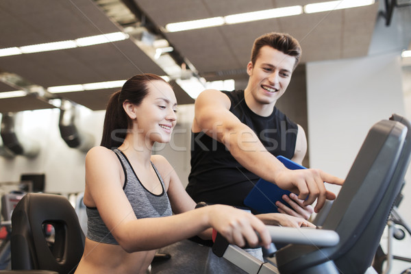 happy woman with trainer on exercise bike in gym Stock photo © dolgachov